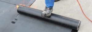 A roofer laying out tarp for roofing